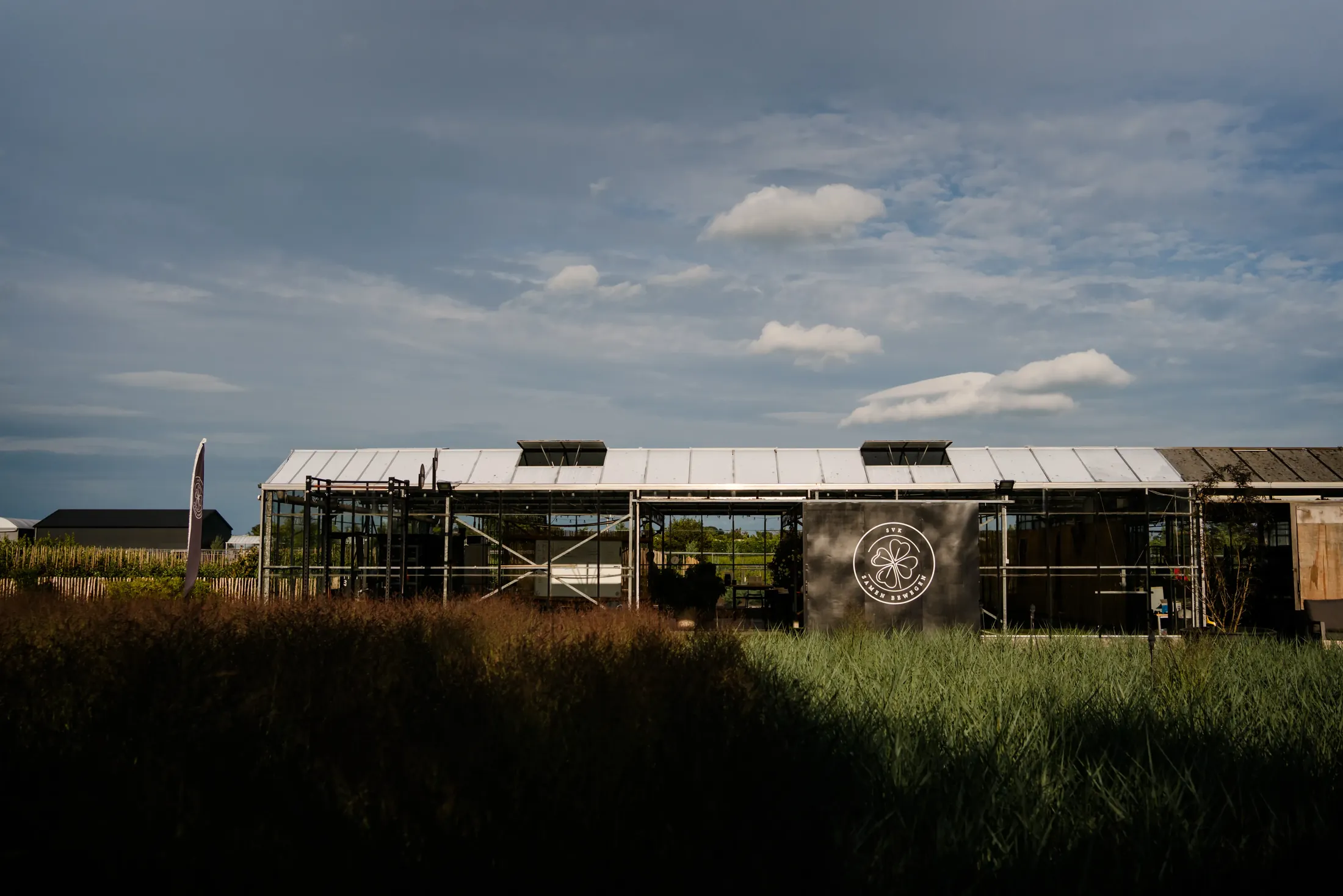 De club vanaf het veld, met hoge grassen op de voorgrond