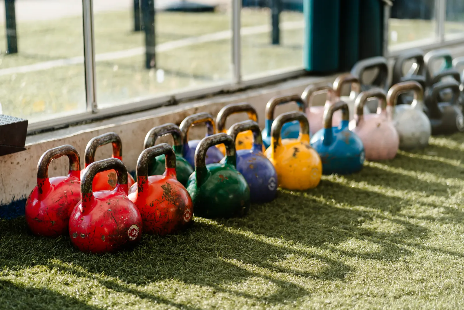 Rij gekleurde kettlebells op het kunstgras in de zon