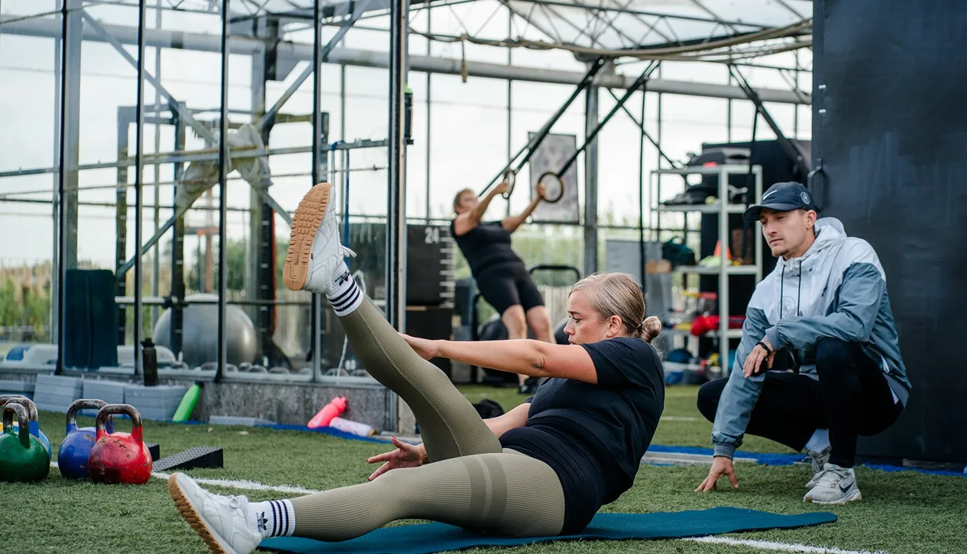 Trainer begeleidt een sporter bij een oefening op de mat